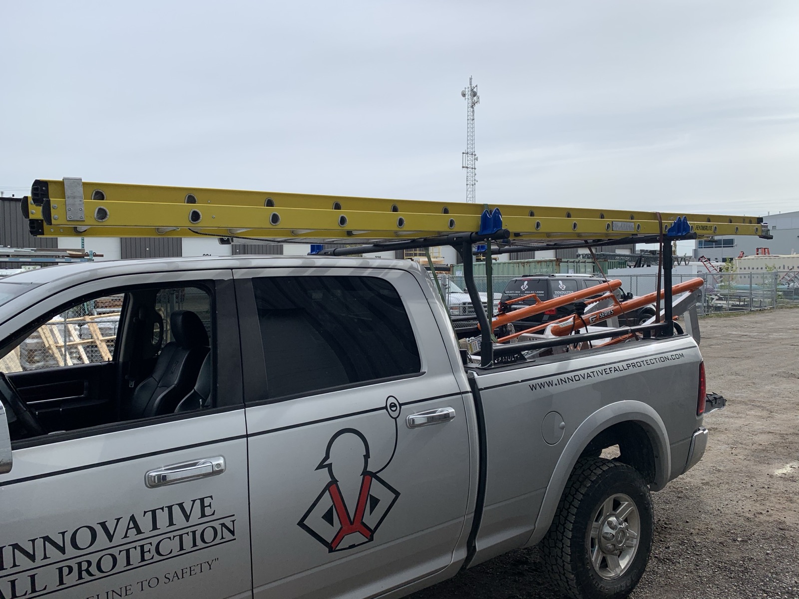 A Frostrack on a work truck carrying a Featherlite extension ladder — headache-rack utility mode